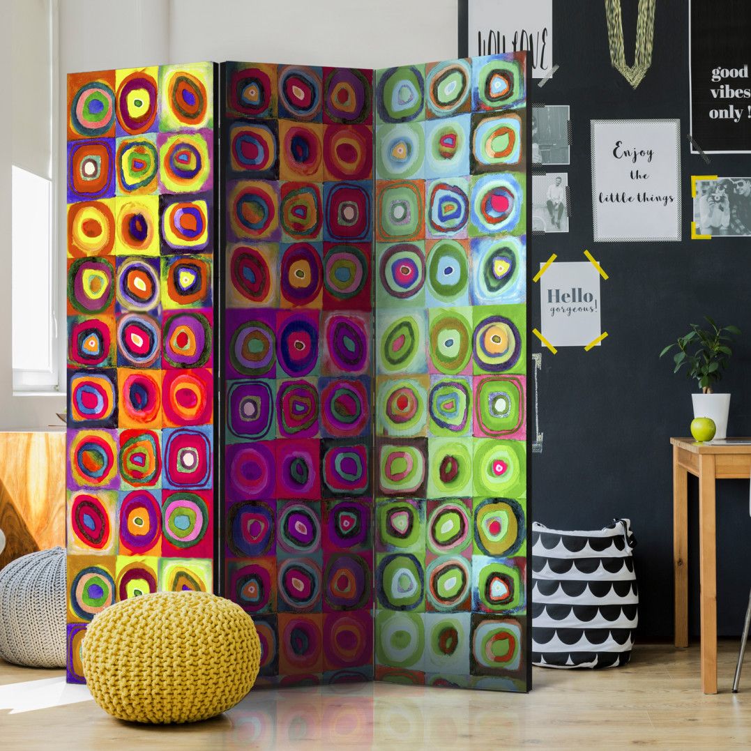 a colorful abstract room divider with 3 panels in a modern and small office room next to posters and a desk