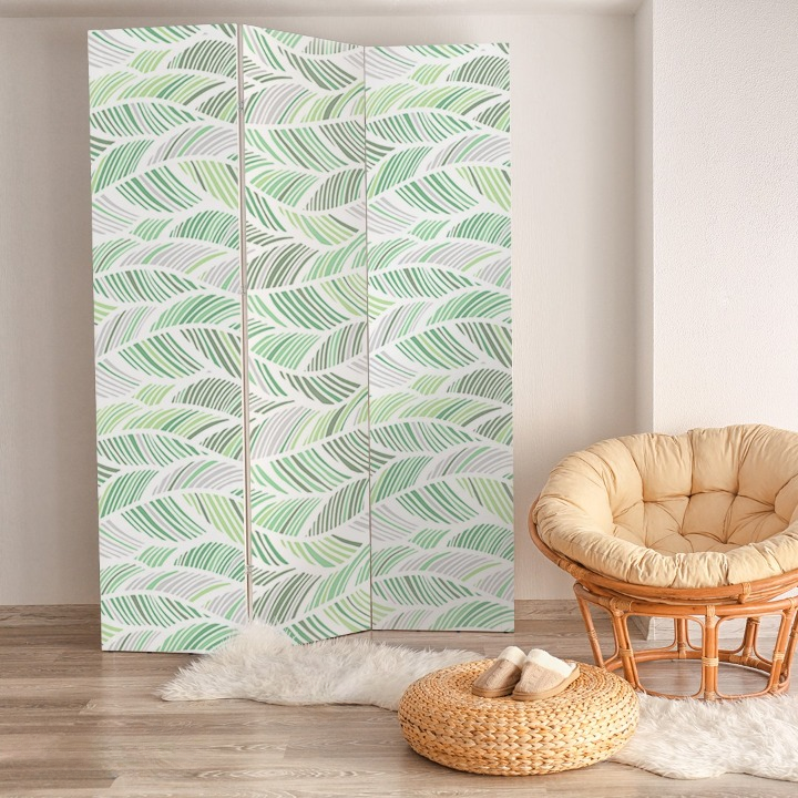 This is a 3 paneled room divider with a botanical design in shades of green and white next to a cosy chair, this is a wonderful partition screen in a UK household