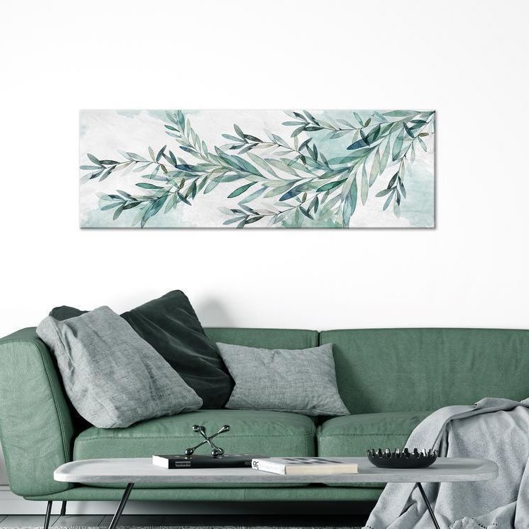 canvas print of leaves mounted on wall and against a green couch