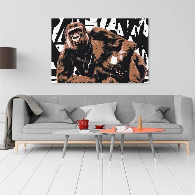 a monkey canvas print sitting sideways while listening to some tunes, this canvas print is posed on a living room with grey sofa against it