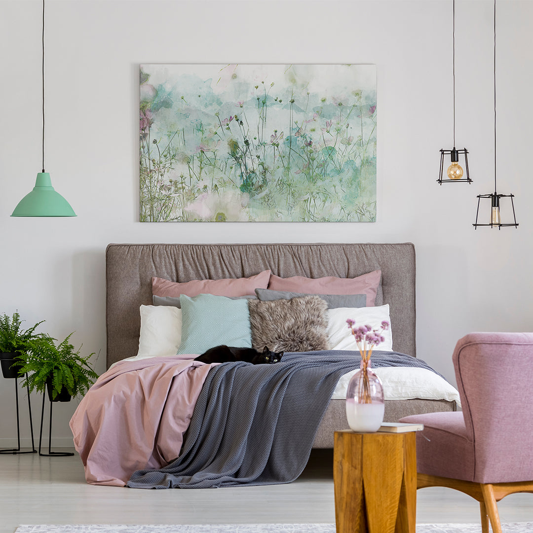 A modern living room features a large canvas print with a geometric design in blue and gray hues hanging above a white couch. A round coffee table with a black metal base and a woven basket underneath complement the space.