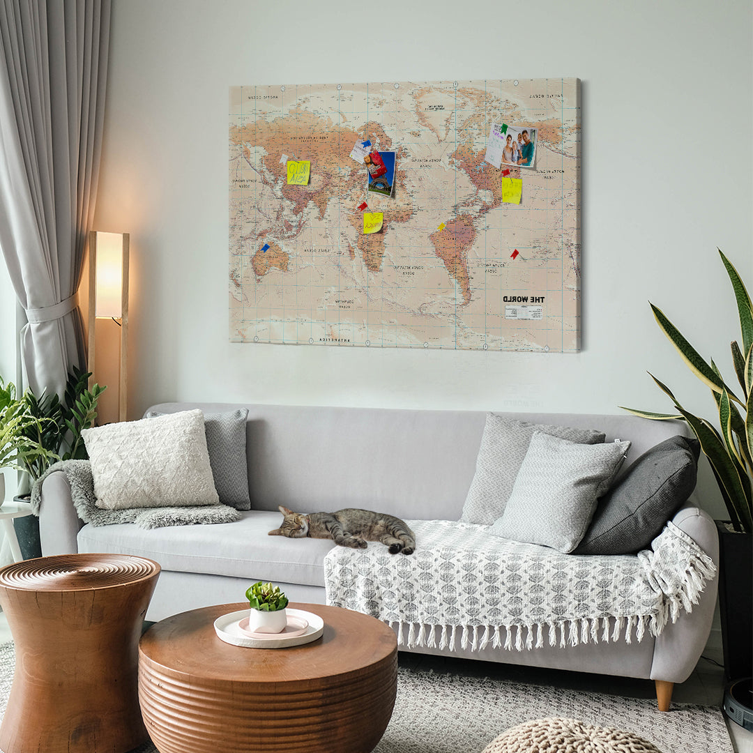 a Pin Board with a world map design mounted on a wall with a cute cat taking a nap on a sofa