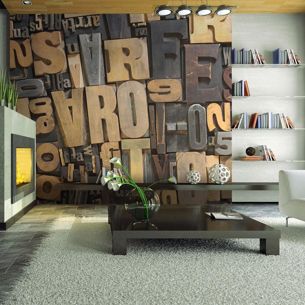 A living room with a fireplace, a coffee table, and a wall covered in decorative wooden letters that appear to spell out random words including “arrt,” “ARTECS,” “Em,” “S,” “a,” and “WROPON.