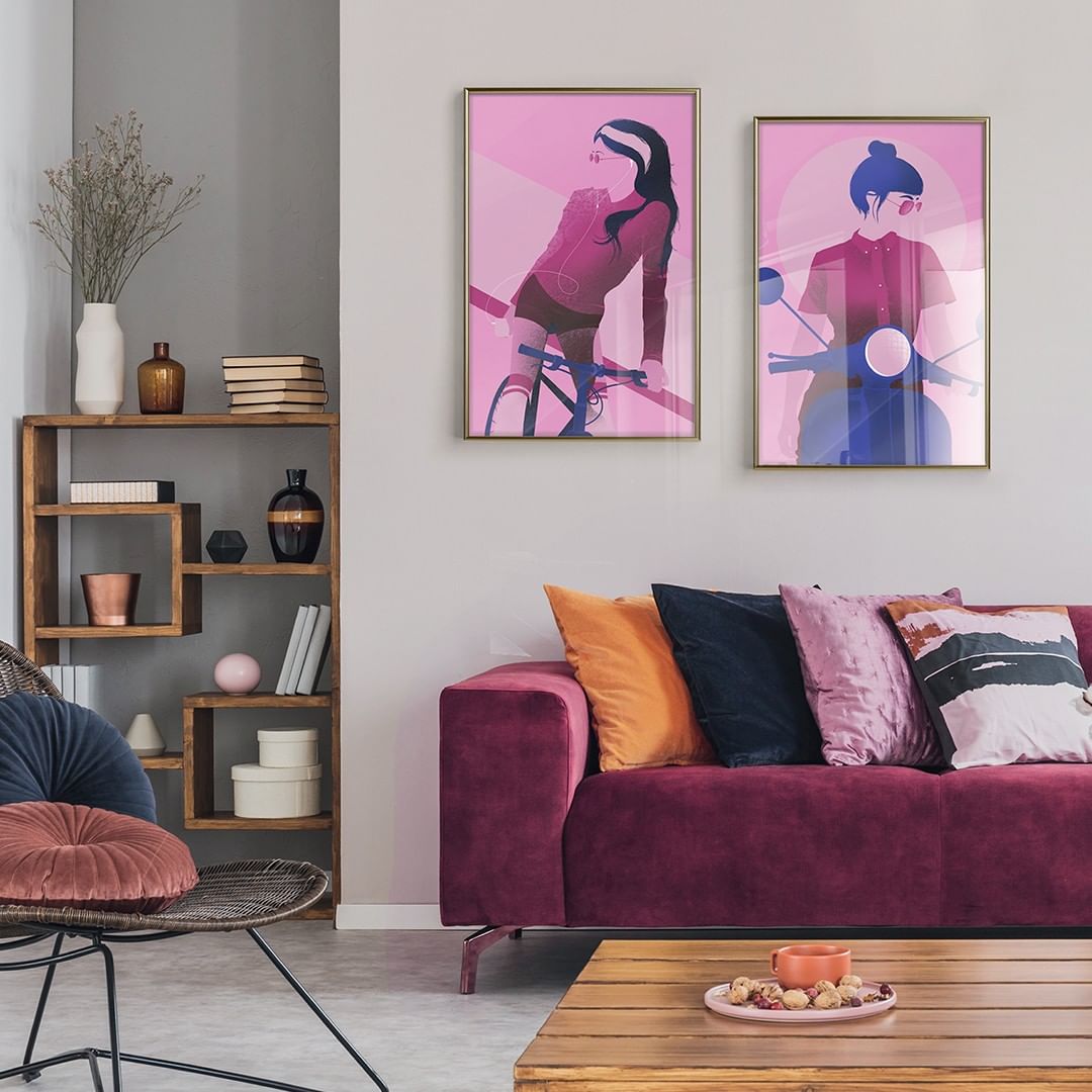 a modern and stylish living room with a dark pink sofa and two people illustration posters made with shades of pink, purple and blue