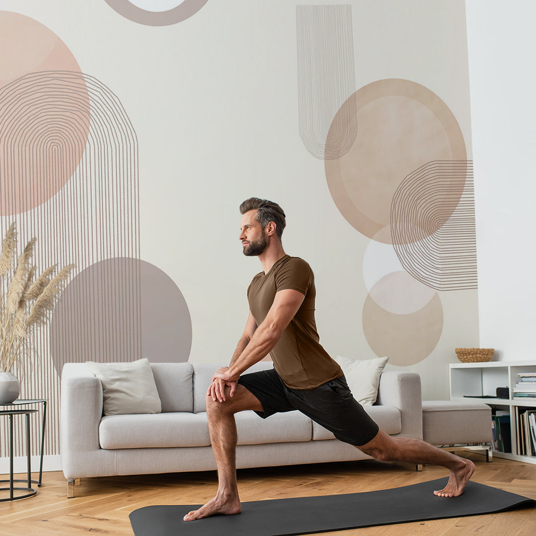 a man doing yoga in their living room and there's an abstract design wall mural behind the living room wall, the man is standing on a yoga mat